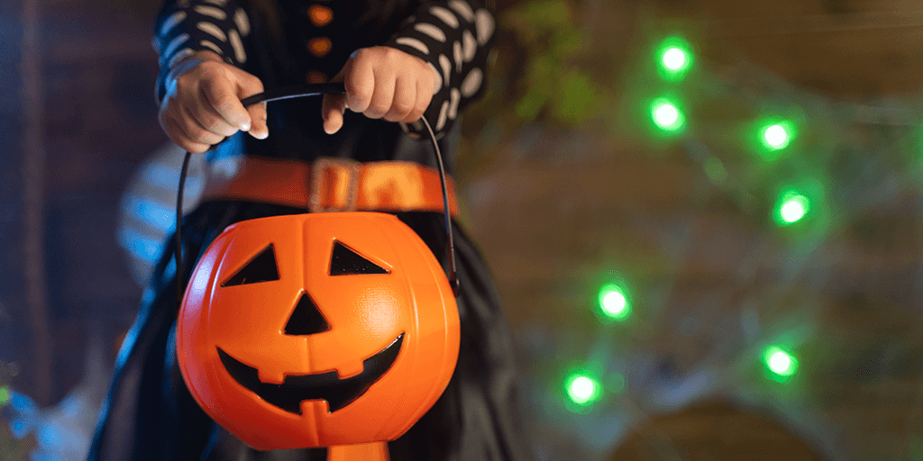 A child holding a pumpkin-shaped basket.