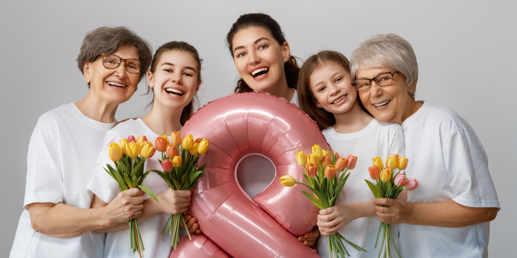 Women of all ages smiling and holding flowers