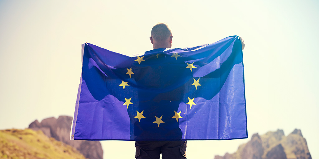 A man holding the EU flag spread across his back.